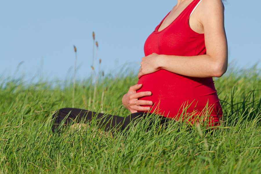 beautiful pregnant woman practicing yoga on a meadow