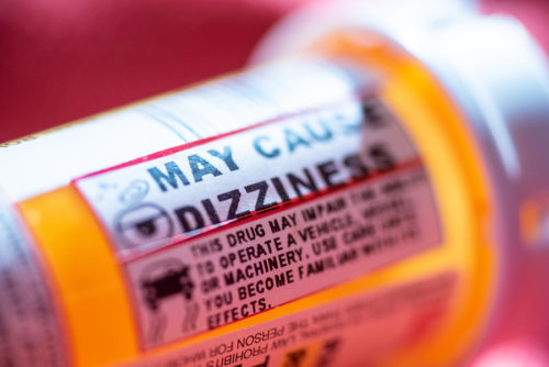 Pill Bottle With Warning Labels Regarding Dizziness And Driving.