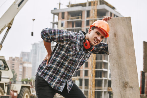 construction worker holding hurt back after injury on the job