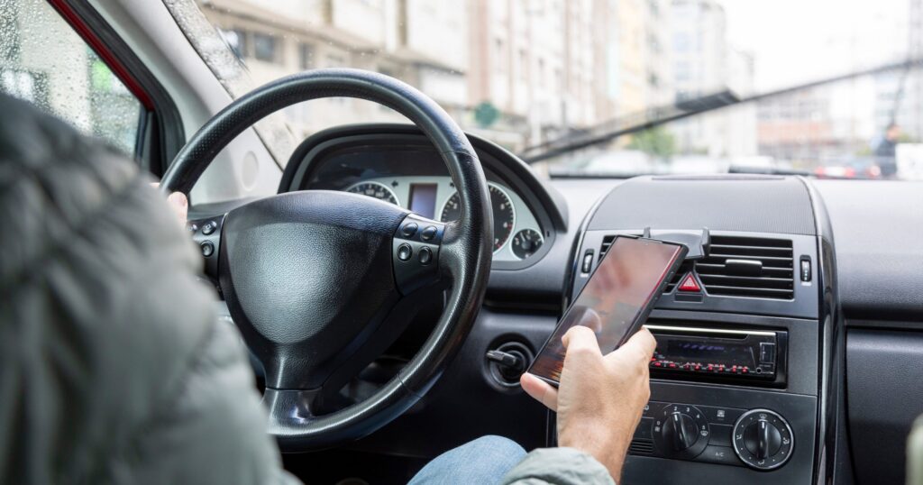 person looking at phone while driving