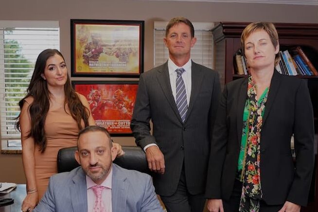 Dolman Law Clearwater Sexual Assault Lawyer Team standing and sitting behind large table