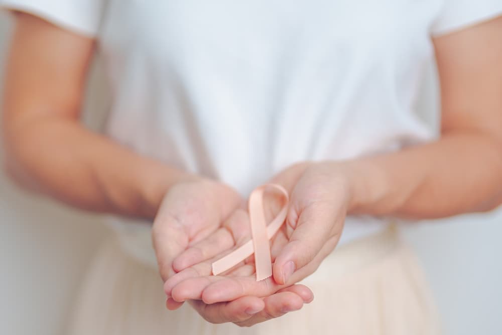 Woman holds a Peach Ribbon for Uterine Cancer Awareness. Symbolizes reproductive health, awareness, and support for uterine-related conditions.