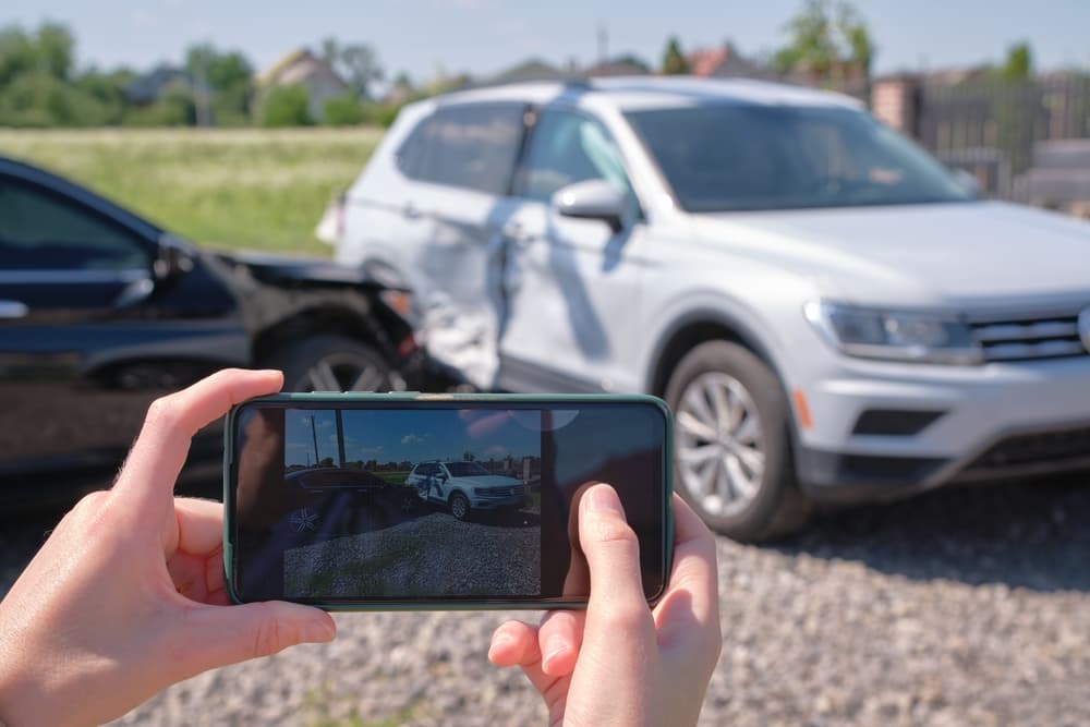 Driver, stressed after car crash, snaps wreckage, seeks emergency help via phone. Emphasizes road safety and insurance.