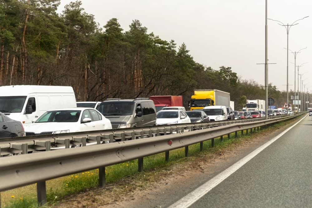 Dixie highway: Car traffic jam, forest backdrop, border control gridlock. Vehicle crash causes freeway bottleneck.