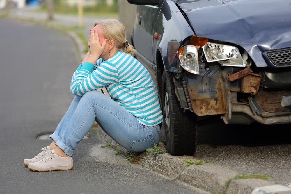 Mujer sentada cerca del coche tras accidente en Denver, Colorado