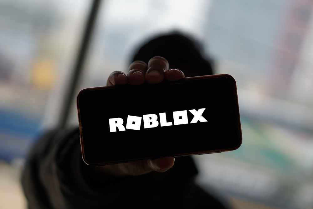 Child holding up phone with Roblox logo - Roblox Sexual Abuse Lawsuit - Roblox Lawsuit