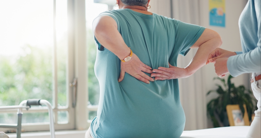 Woman experiencing back pain due to a defective spinal cord stimulator.